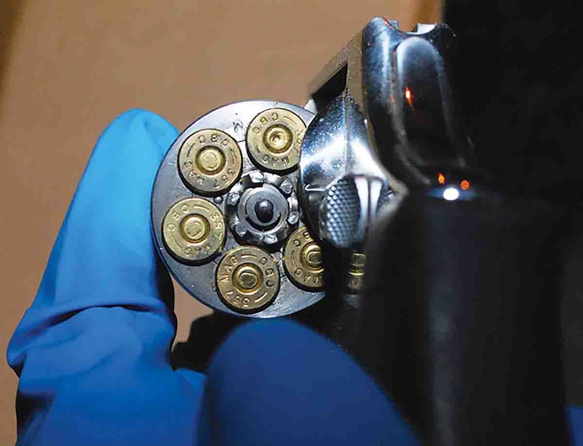 A forensic examiner displays the five unfired cartridges and one fired case of the snub-nose revolver found near the homicide scene. Later ballistic comparisons would find that the bullet taken from the victim was consistent with this firearm.